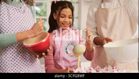 Baking, cupcakes and child with parents in kitchen for learning, bonding or development in home. Smile, cooking and girl kid with mother and father Stock Photo