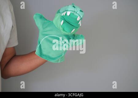 Fun green dinosaur puppet in playful hand performance Stock Photo