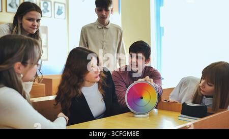 Students in physics class spin Newton's multicolored disk. Stock Photo