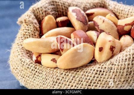 Close-up of raw Brazil nuts in a rustic burlap sack, showcasing their natural texture and earthy tones. Copy space to left Stock Photo