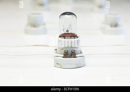 A connected circuit on a white surface of incandescent lamps mounted on a base and connected by wires. Stock Photo