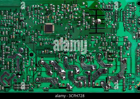 Green printed circuit board with radio components on background. Vintage circuit board with soldering trace, parts and microcircuits, close up, top vi Stock Photo