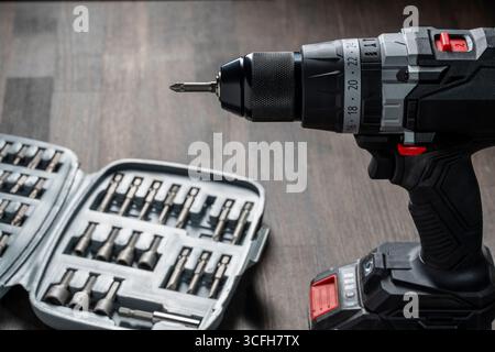 Battery cordless screwdriver and set screwdriver bits on a wooden background, close up Stock Photo