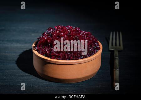 Beetroot salad in a bowl and fork on wooden table background, close up. Grated boiled red beetroot in a clay bowl. Dieting and vegetarian concept. Sna Stock Photo