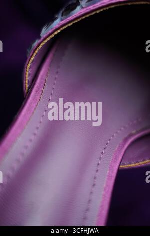 A detailed close-up reveals the textured surface of purple leather, showcasing fine stitching and the subtle variations in its tone. The soft lighting Stock Photo