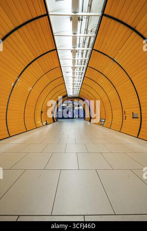 Long, illuminated underground railway tunnel in bright orange, leading into the distance, Marienplatz Munich, Germany Stock Photo