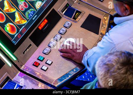 Hand pressing button on slot machine in casino Stock Photo