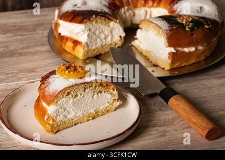 A slice of Roscon de Reyes filled with cream on a plate, a traditional sweet served on Epiphany. Stock Photo