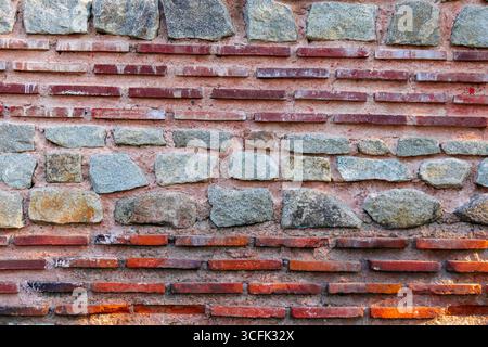 A textured wall displays a mix of stones and bricks arranged in a unique pattern. The combination of colors and materials creates an interesting visua Stock Photo