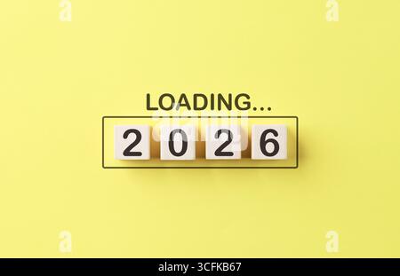 Loading 2026 New Year Progress Concept. Wooden cubes number 2026 inside progress bar with word loading on bright yellow background, Stock Photo