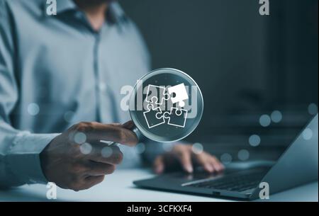 Business solutions concept. Success strategy of business. Businessman holding magnifying glass focusing on jigsaw puzzle. Leadership strategy. Creativ Stock Photo