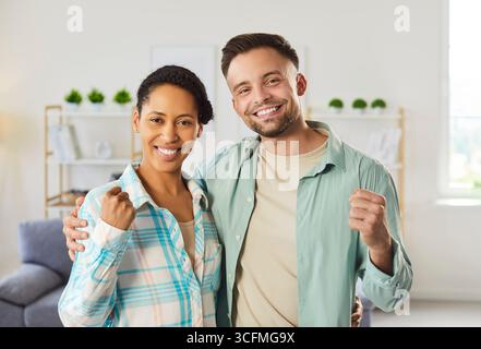 Woman and man embracing and clenching fists, having positive mood, feeling glad, working as team Stock Photo