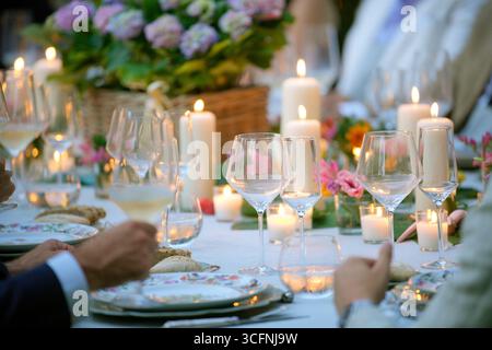 Elegant outdoor dinner party with candles illuminating the table and wine glasses ready for a toast Stock Photo