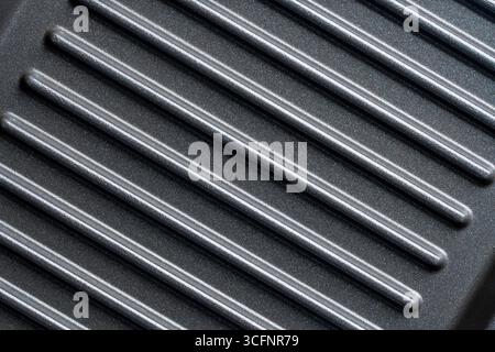 Black grill non-stick die-cast aluminum plates for design purpose, close up, top view. Electric grill plate as background or texture. ribbed striped g Stock Photo