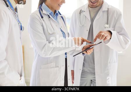 Cropped shot of unknown team of medical workers or doctors wearing white medical coats, using tablet Stock Photo