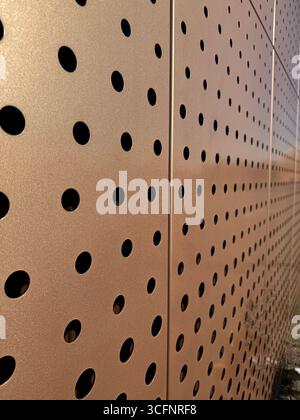 A patterned metal surface with circular holes, blends aesthetics and function in design Stock Photo