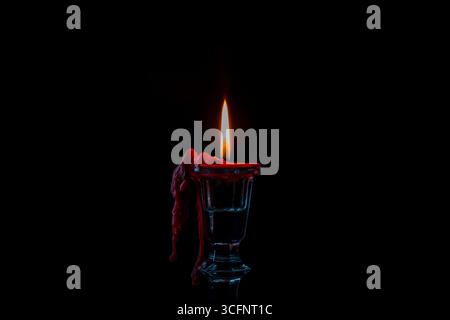 Glass candlestick with red burning candle on black background, close up Stock Photo