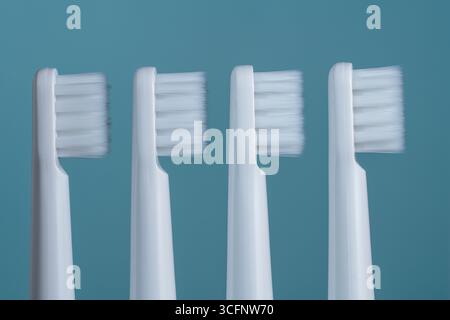 Four white plastic toothbrushes on a blue background, close up Stock Photo