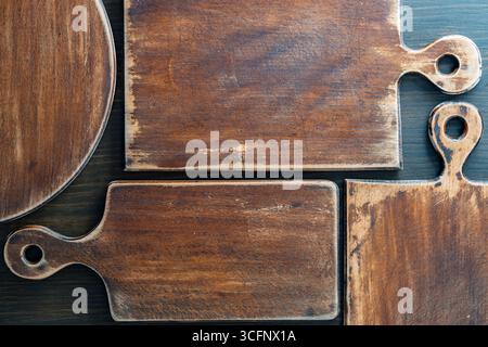 Three old retro cutting boards of various shapes on wooden background, close up Stock Photo