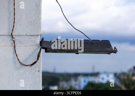 Close-up of a modern outdoor halogen LED security light fixture mounted on a building wall below the roofline, providing bright illumination for the p Stock Photo