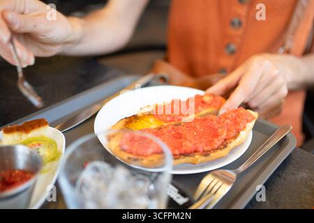 Woman having a catalan breakfast with toasted bread and crushed tomatoes, enjoying local cuisine Stock Photo