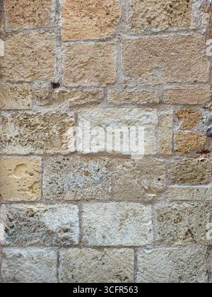 Closeup of weathered stone wall surface made of rectangular blocks showing cracks, natural textures and rustic details Stock Photo