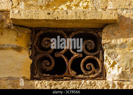 Rustic Window With Decorative Iron Bars on Stone Wall Stock Photo