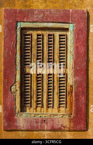 Rustic Yellow Wooden Window With Red Frame on a Textured Wall Stock Photo