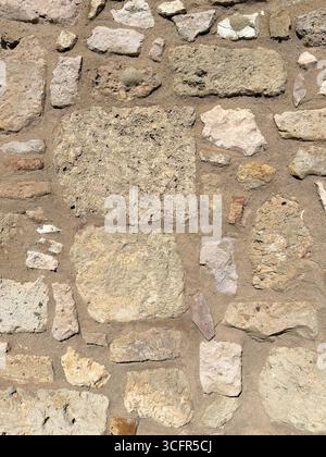 Detailed closeup of weathered stone masonry wall built with irregular rocks and mortar Stock Photo