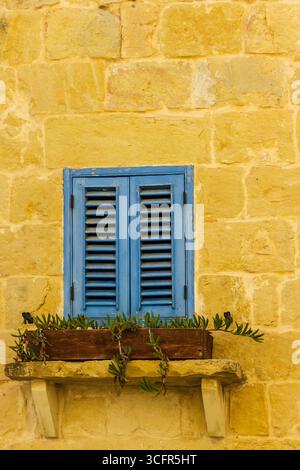 Rustic Stone Wall with Blue Shuttered Window and Wooden Flower Box Stock Photo