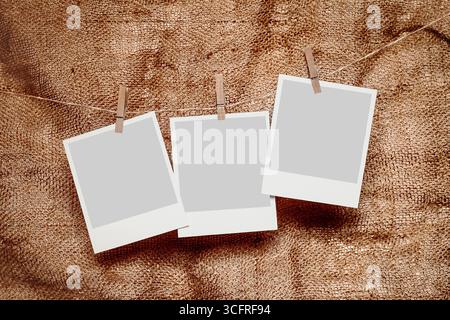 Three retro photo frames hang on a rope against a background of burlap fabric Stock Photo