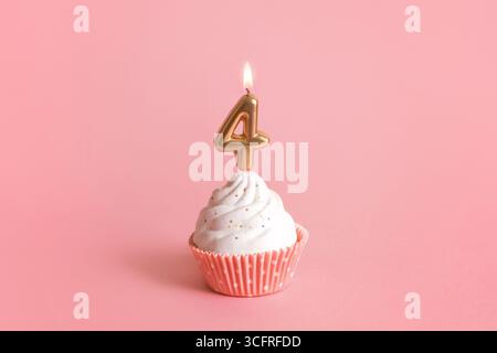 Birthday cupcake with number four candle on pink background. birthday cake with a candle in the shape of the number four Stock Photo