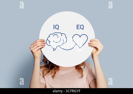 iq eq concept. girl holding poster with hand drawing a brain and heart. IQ intelligence quotient and EQ emotional intelligence concept Stock Photo