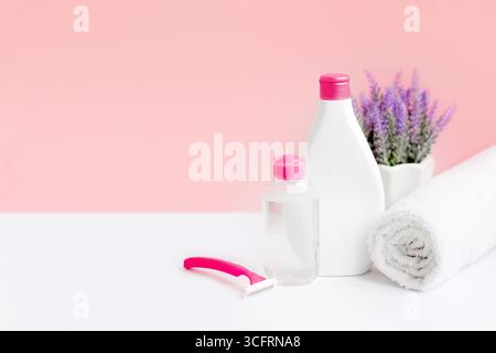 Hygiene and body care. Micellar water body lotion, towel, razor, cotton pads on pink background, spa and female treatments. Epilation concept Stock Photo