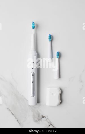A white ultrasonic toothbrush with interchangeable heads on and dental floss. Oral and dental care Stock Photo