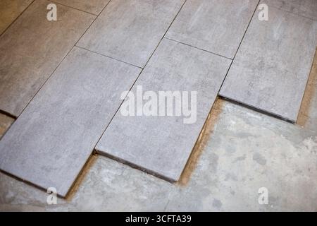 Close-up of large format ceramic tiles being laid on cement screed. Stock Photo