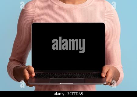 Nice Website. Smiling Young African American Woman Holding Laptop With Black Screen Stock Photo