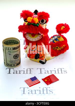 A Lion dance toy, a roll of US Dollar bills, and the Chinese and American national flags isolated on a white background with the words tariff, tariffs Stock Photo