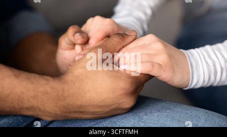 Cropped Image Of Romantic Interracial Couple Holding Hands Together Stock Photo