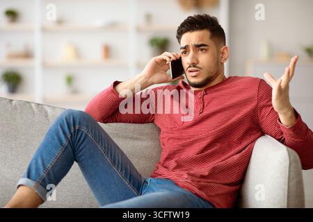 Irritated arab guy having conversation on phone Stock Photo