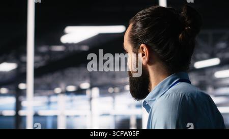Data center programmer using laptop to monitor neural network using AI LLM chatbot. Worker using artificial intelligence on notebook to oversee servers powering machine learning, camera A Stock Photo