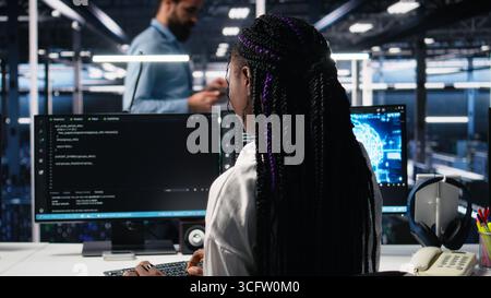 Technicians in data center review AI diagnostics, analyzing neural network performance to maintain operational reliability. IT workers optimize artificial intelligence systems configuration, camera A Stock Photo