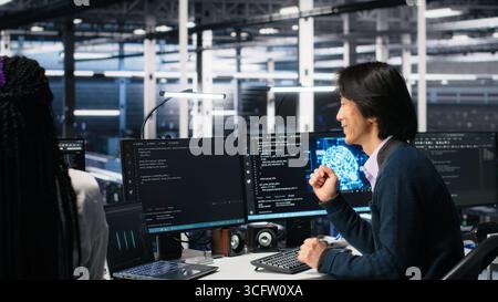 Delighted team in data center celebrating finishing neural network software development. Ecstatic coworkers doing high five in server room after successfully implementing machine learning, camera A Stock Photo