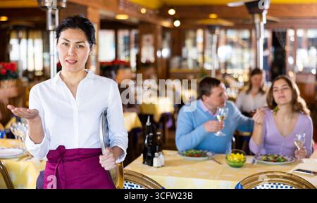 Polite smiling asian waitress inviting to cozy restaurant Stock Photo ...