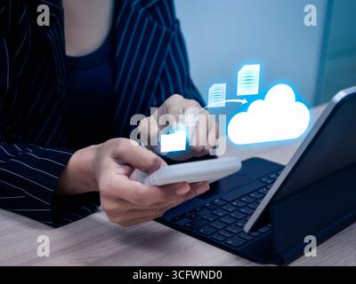 Businesswoman using smartphone and tablet to upload documents to cloud storage, concept of cloud technology, secure data transfer, file sharing and di Stock Photo