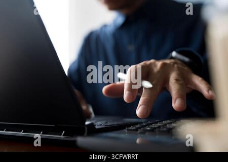 Closeup of businessman working on laptop with digital pen for financial data analysis, investment planning, technology innovation, banking management, Stock Photo