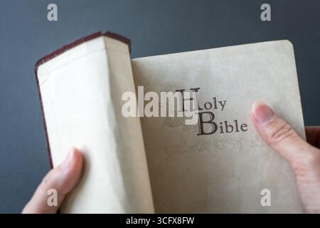 Opening a used old Holy Bible. Closed up view. Stock Photo