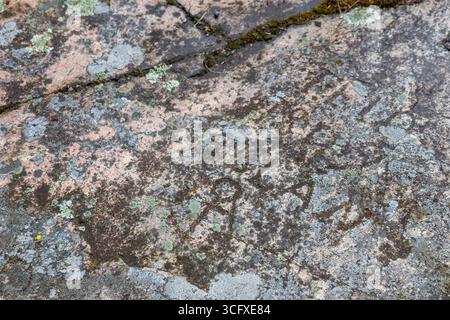 Close-up of weathered stone with carved historic dates and symbols. Deep grooves, rough texture, and aged patina, history, memory, and timeless northe Stock Photo