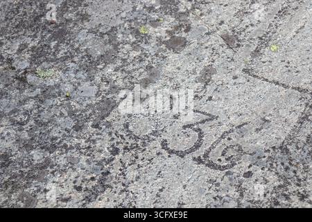 Close-up of weathered stone with carved historic dates and symbols. Deep grooves, rough texture, and aged patina, history, memory, and timeless northe Stock Photo