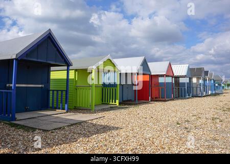 A row of traditional wooden beach huts on the coast. Colourful seaside beach cabins Stock Photo